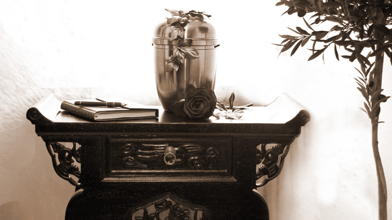 Foto einer Urne und eines Kondolenzbuchs auf einem kleinen Tisch